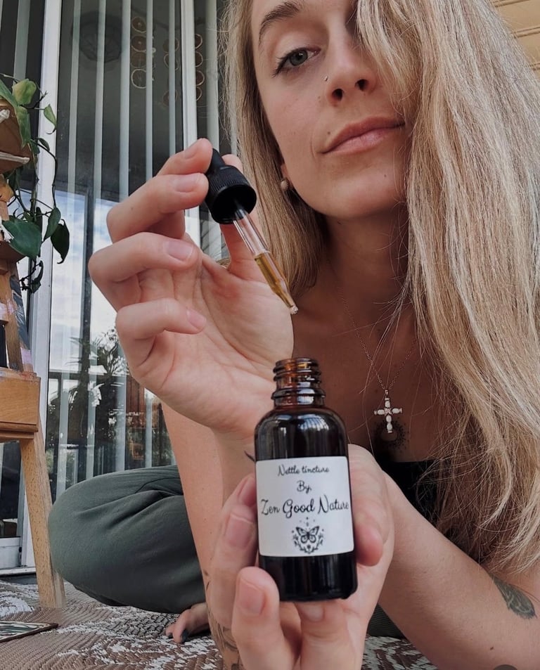 Woman holding a glass dropper bottle of essential oil or wellness product labeled Zen Good Vibes